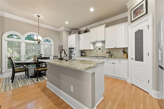 kitchen featuring crown molding, appliances with stainless steel finishes, white cabinets, decorative light fixtures, and light wood-style floors