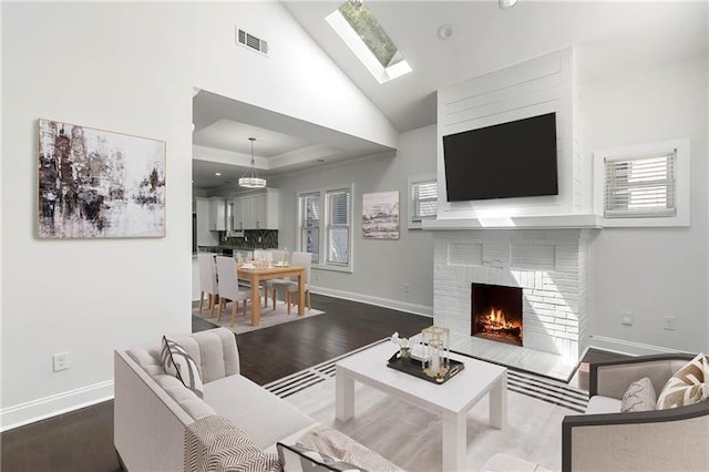 living room featuring hardwood / wood-style flooring, a brick fireplace, plenty of natural light, and lofted ceiling