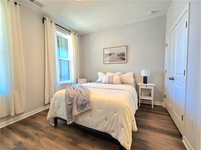 bedroom with dark wood finished floors, visible vents, and baseboards