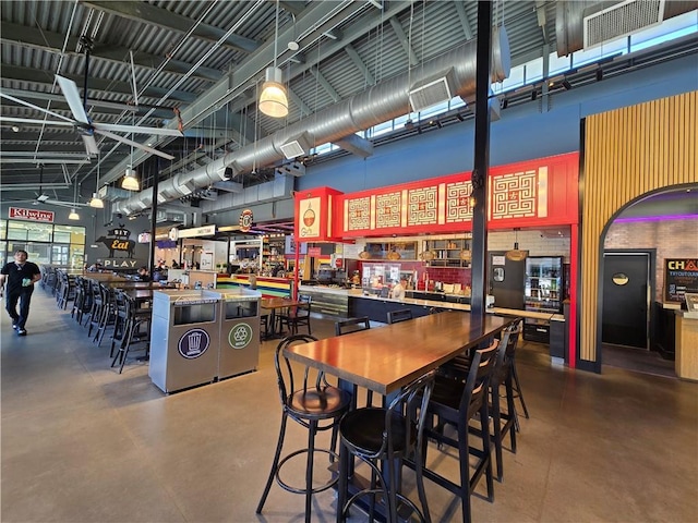 dining area featuring concrete floors and a high ceiling