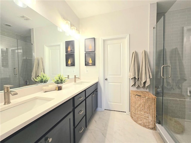 bathroom with double vanity, marble finish floor, a shower stall, and a sink