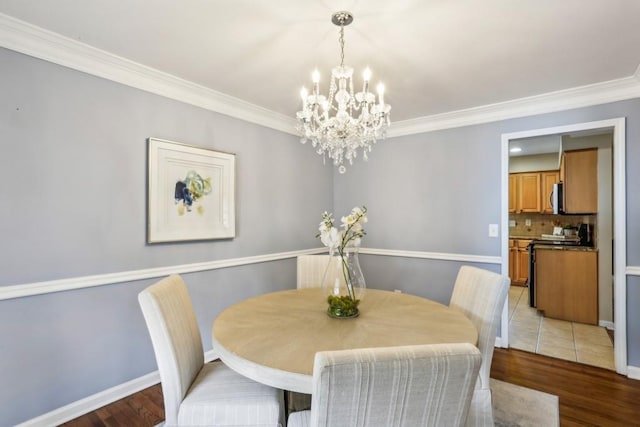 dining room with wood-type flooring, ornamental molding, and a chandelier