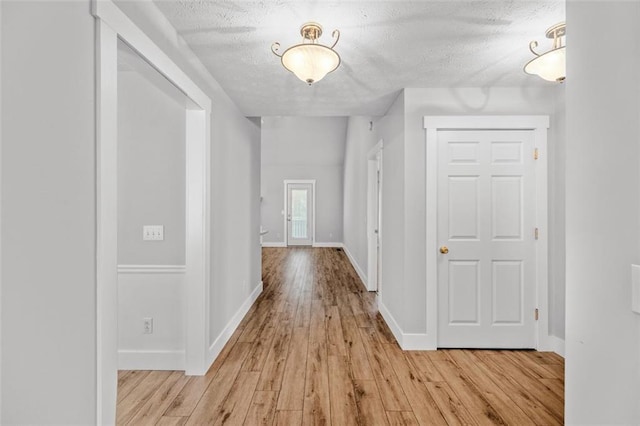 hall with a textured ceiling and light wood-type flooring