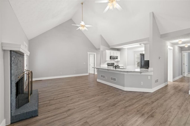 living room featuring sink, hardwood / wood-style floors, a brick fireplace, high vaulted ceiling, and ceiling fan