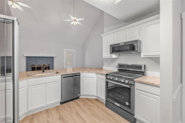 kitchen with white cabinetry, light hardwood / wood-style flooring, appliances with stainless steel finishes, and lofted ceiling