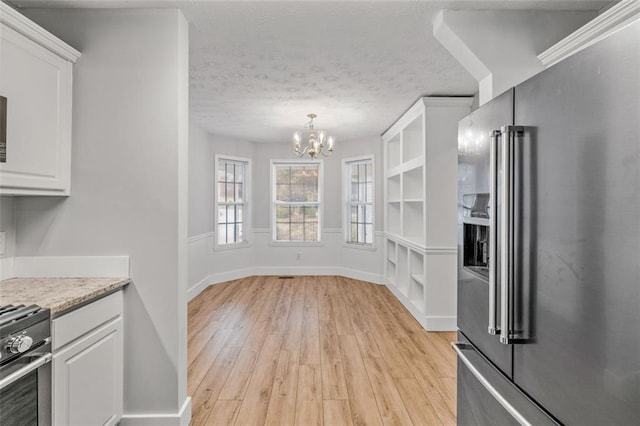 kitchen with light hardwood / wood-style flooring, white cabinets, pendant lighting, a chandelier, and appliances with stainless steel finishes