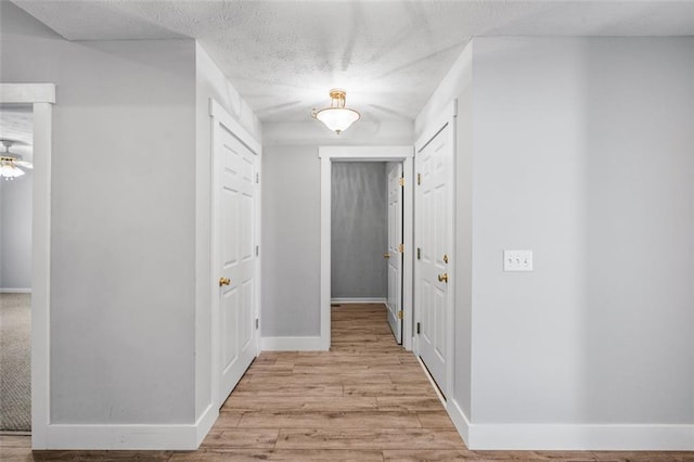 hallway with light hardwood / wood-style floors and a textured ceiling