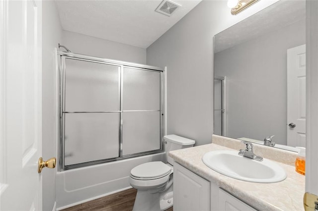 full bathroom featuring vanity, toilet, hardwood / wood-style flooring, and enclosed tub / shower combo