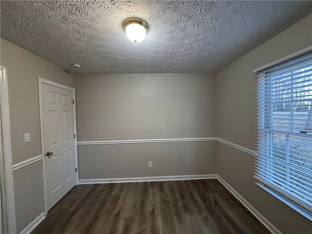 spare room with a textured ceiling and dark hardwood / wood-style flooring