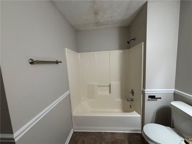 bathroom featuring a textured ceiling, toilet, and shower / bath combination