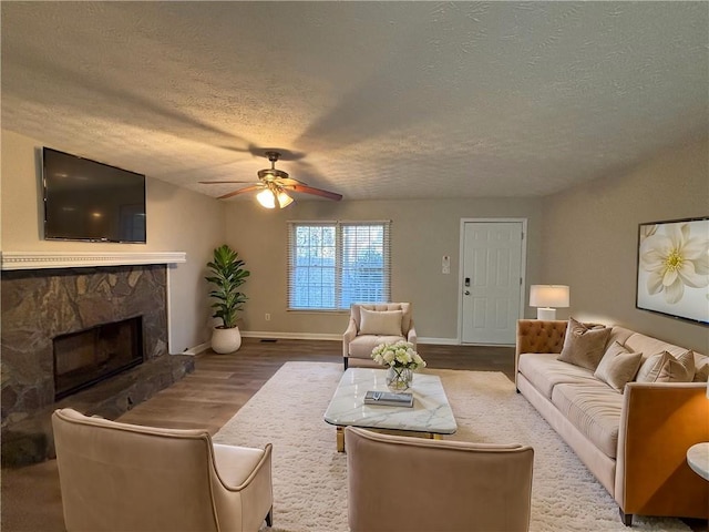 living room with hardwood / wood-style floors, a fireplace, a textured ceiling, and ceiling fan