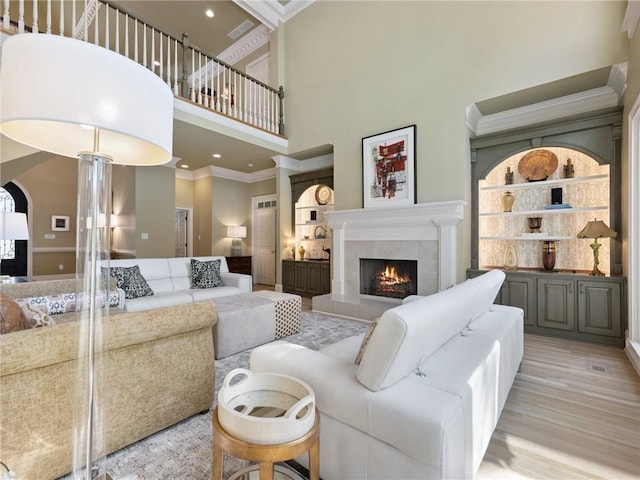 living area featuring visible vents, wood finished floors, ornamental molding, and a high end fireplace