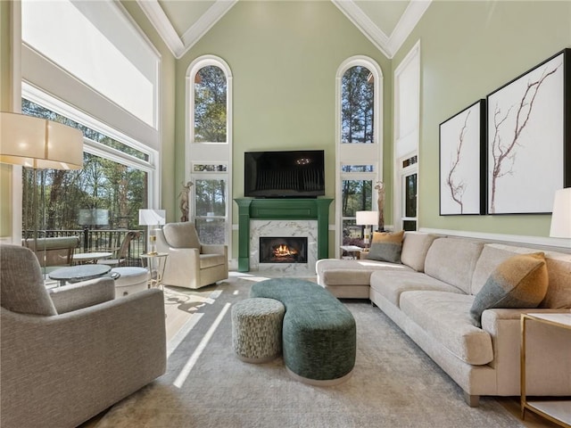 living room with high vaulted ceiling, crown molding, and a premium fireplace