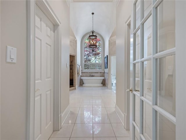 hall with an inviting chandelier, light tile patterned flooring, and vaulted ceiling