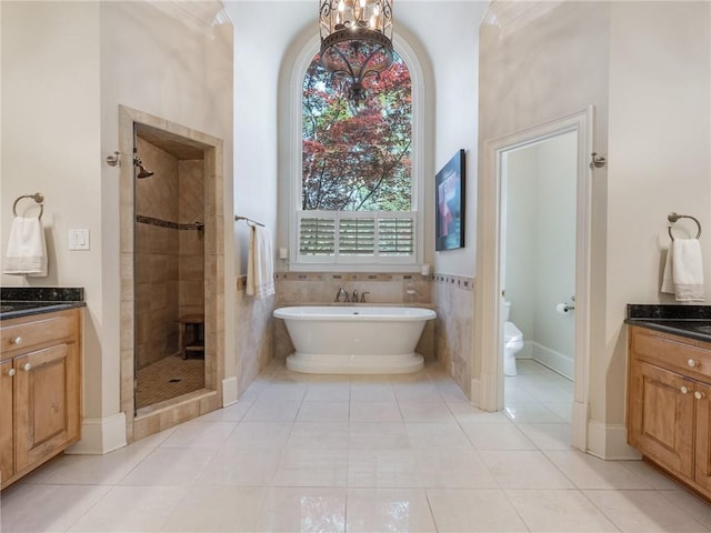 full bath with toilet, a freestanding bath, a stall shower, tile patterned floors, and vanity