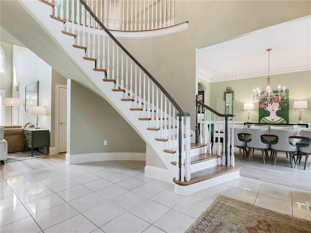 stairway featuring tile patterned floors, baseboards, a towering ceiling, and a chandelier