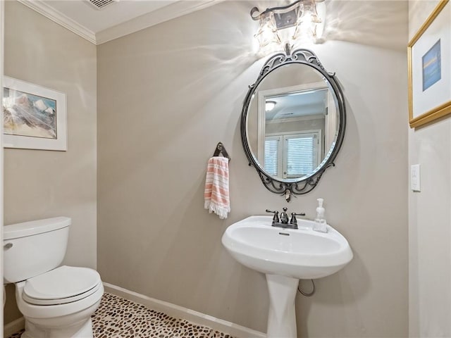 half bathroom with crown molding, toilet, and baseboards