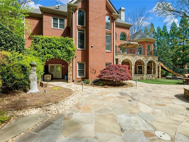 back of property featuring brick siding, a patio area, and a chimney