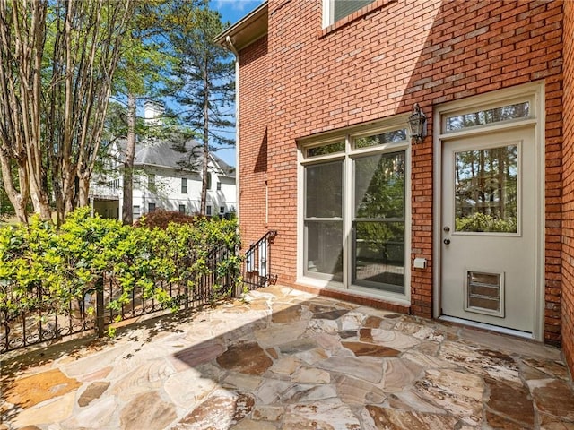 entrance to property featuring brick siding and a patio area