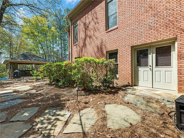 view of side of home featuring a gazebo and brick siding