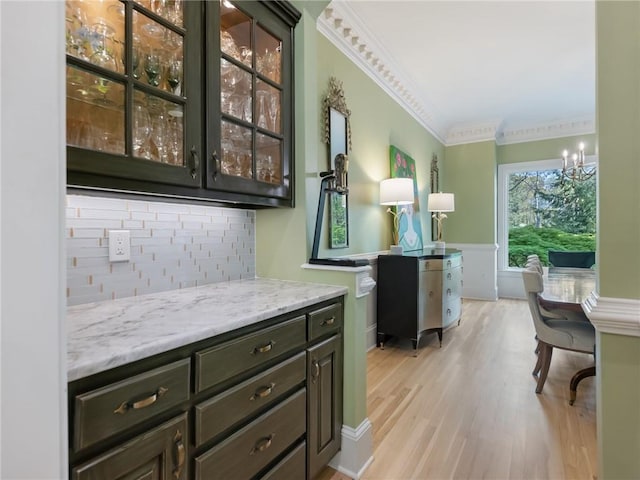 bar featuring decorative backsplash, light wood-style flooring, a chandelier, and ornamental molding