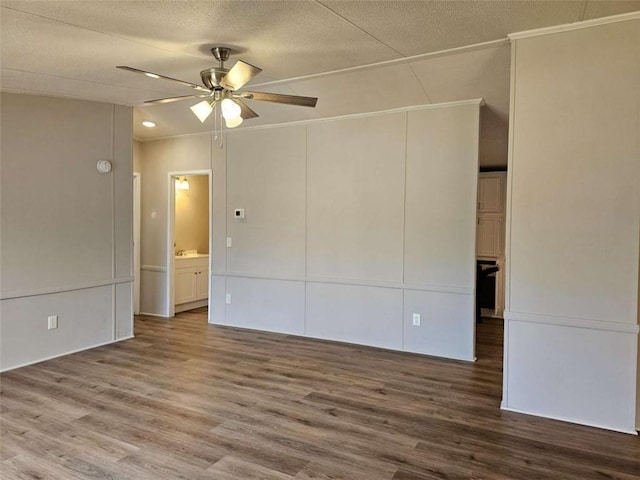 unfurnished room featuring a textured ceiling, a ceiling fan, wood finished floors, and ornamental molding