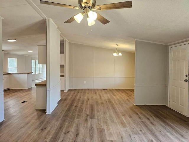 unfurnished room with light wood finished floors, visible vents, vaulted ceiling, and ceiling fan with notable chandelier