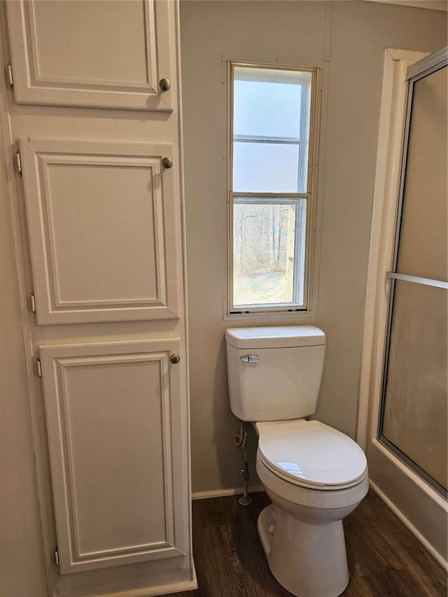 bathroom featuring toilet, baseboards, an enclosed shower, and wood finished floors