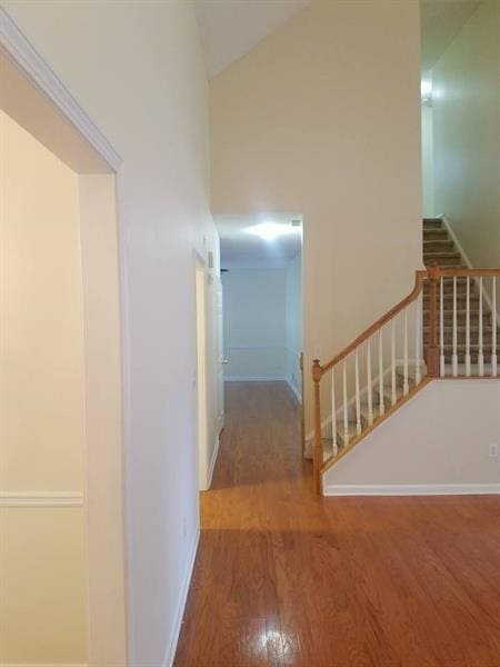 interior space with stairway, baseboards, high vaulted ceiling, and wood finished floors