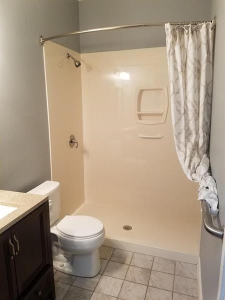 bathroom with vanity, tile patterned floors, a shower stall, and toilet