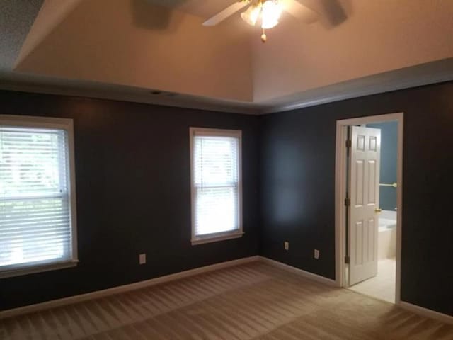 empty room featuring light colored carpet, baseboards, ceiling fan, and vaulted ceiling