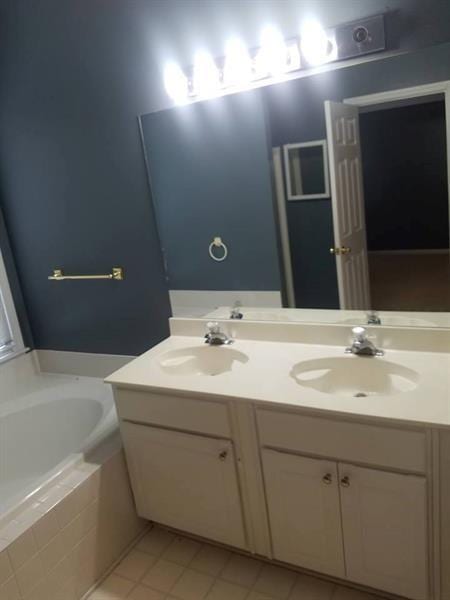 bathroom featuring double vanity, tile patterned floors, a sink, and a bath