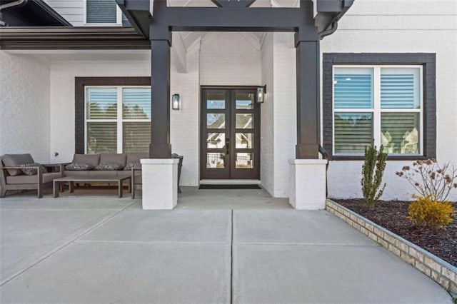 view of exterior entry featuring brick siding, french doors, and outdoor lounge area