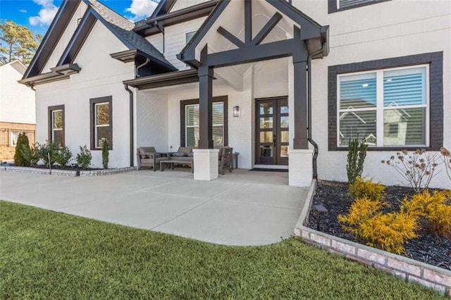 doorway to property with a patio, french doors, brick siding, and stucco siding