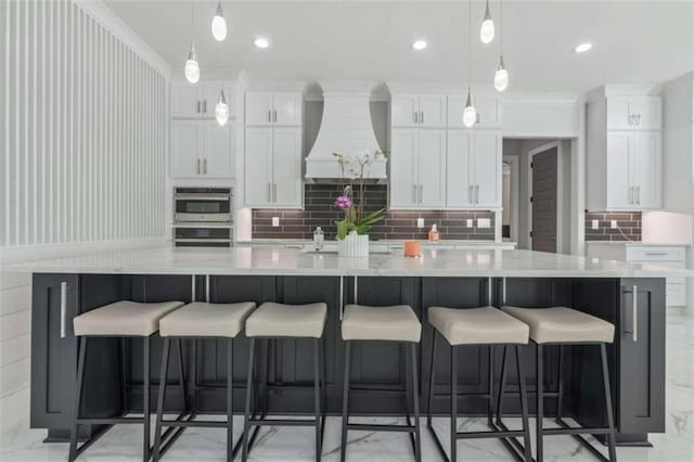 kitchen featuring double oven, a large island, white cabinets, custom exhaust hood, and marble finish floor