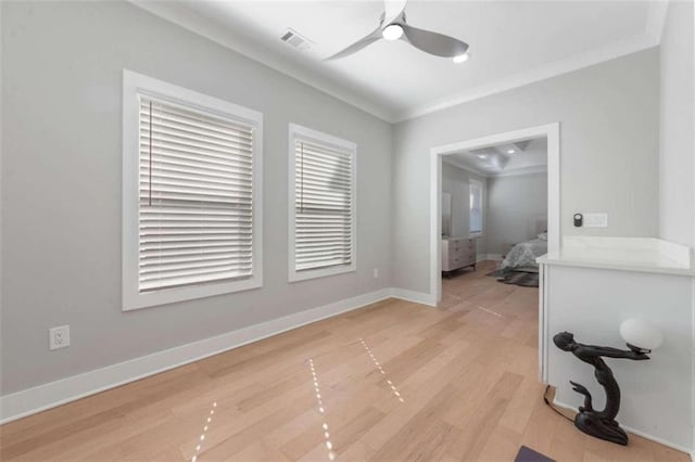 interior space featuring light wood-type flooring, visible vents, baseboards, and crown molding