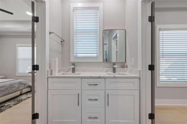 full bath with a sink, baseboards, and double vanity