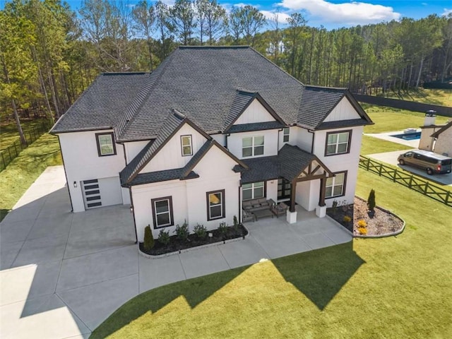 modern farmhouse style home featuring a shingled roof, a front lawn, and fence