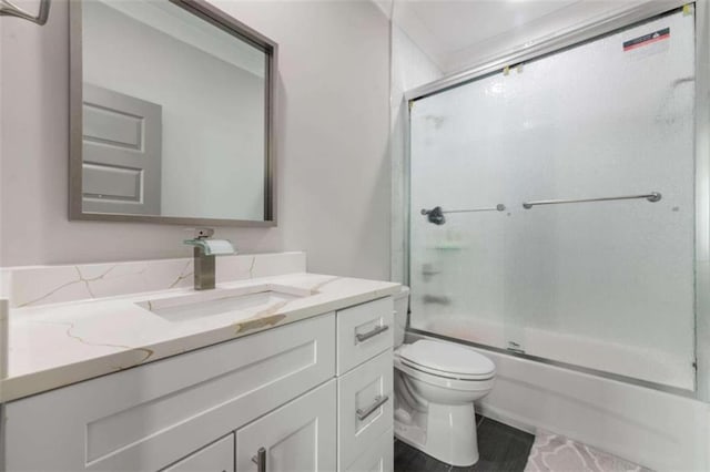 bathroom featuring vanity, toilet, and shower / bath combination with glass door