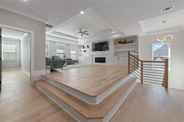 interior space featuring visible vents, built in shelves, wood finished floors, a fireplace, and ceiling fan