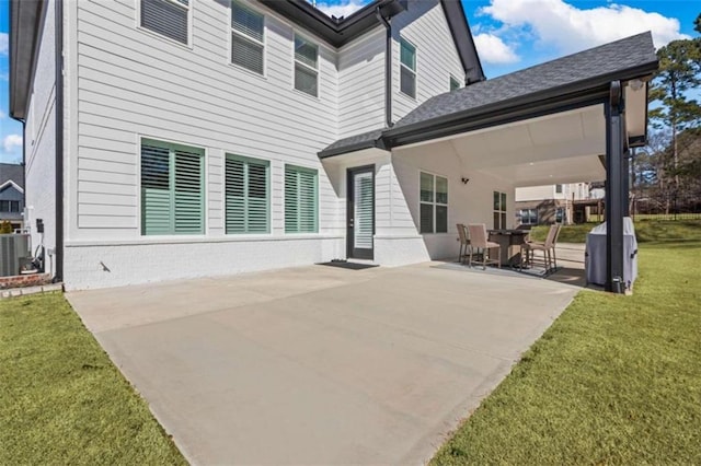 back of property with brick siding, a lawn, central AC, and a patio