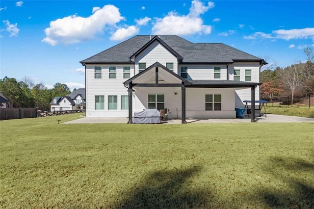 rear view of house with a lawn, a patio, and fence