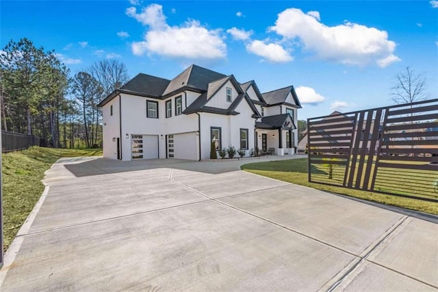 view of front facade with a front lawn, fence, concrete driveway, stucco siding, and a garage