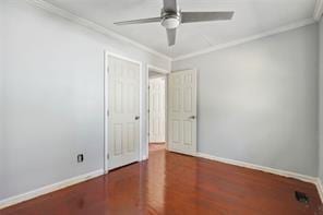 spare room with dark wood-type flooring, crown molding, and ceiling fan