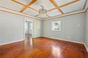 spare room with an inviting chandelier, beam ceiling, coffered ceiling, and wood-type flooring