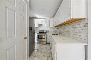 kitchen with appliances with stainless steel finishes, decorative backsplash, white cabinets, and sink