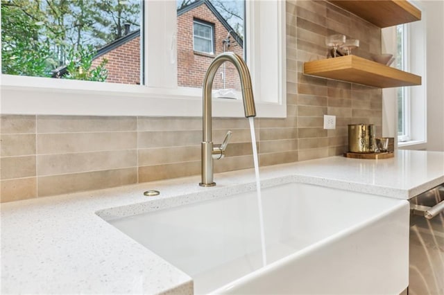 room details with backsplash, light stone countertops, and sink