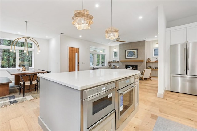 kitchen featuring appliances with stainless steel finishes, a large fireplace, pendant lighting, and a notable chandelier