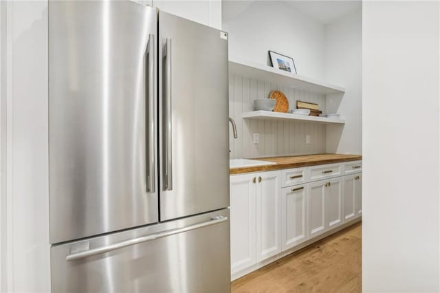 kitchen featuring wood counters, sink, light hardwood / wood-style floors, white cabinetry, and stainless steel refrigerator