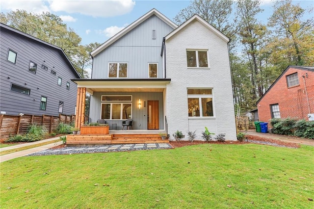 back of property with a lawn and covered porch